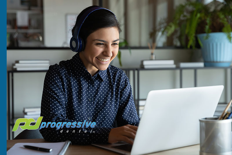 a dental marketing specialist smiling and posting a stock blog on a laptop.