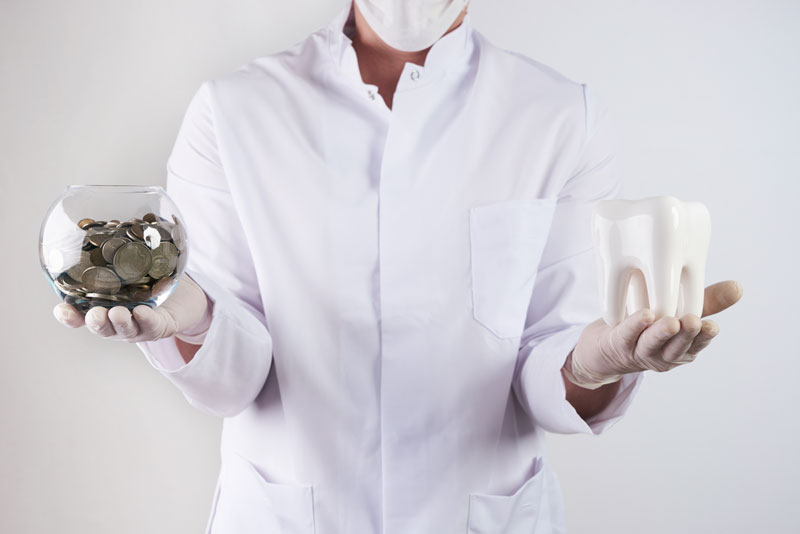 an implant dentist holding a dental implant model and a jar of coins.