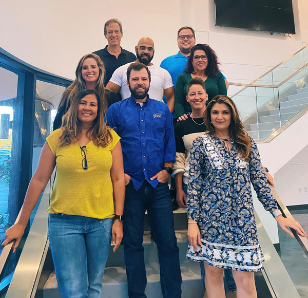 progressive dental marketing team mebers on a staircase smiling.