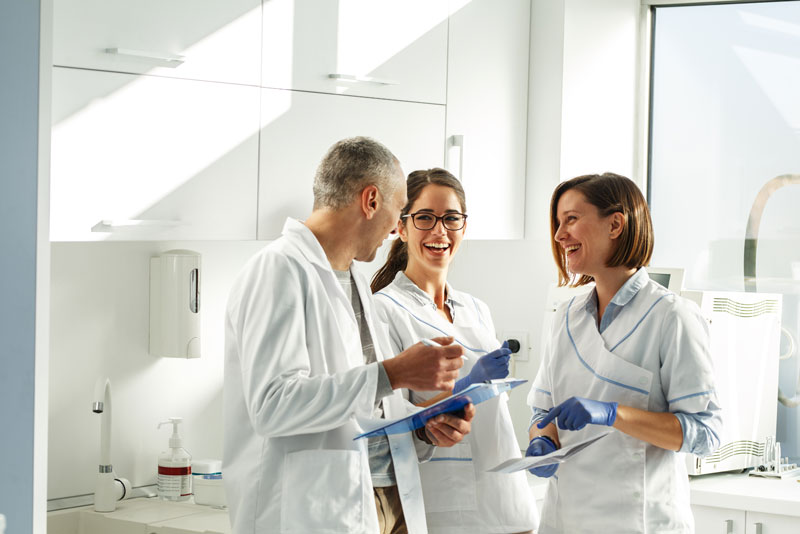 a team of dentists meeting over schedule changes in a dental lab.