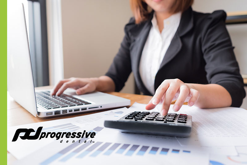 a dental assistant reconciling the financial accounts at a dental practice.|a dental assistant reconciling the financial accounts for a dental practice.|a pen and calculator used for financial bookkeeping.|progressive dental team members in the seasonal spirit at the clearwater florida office.