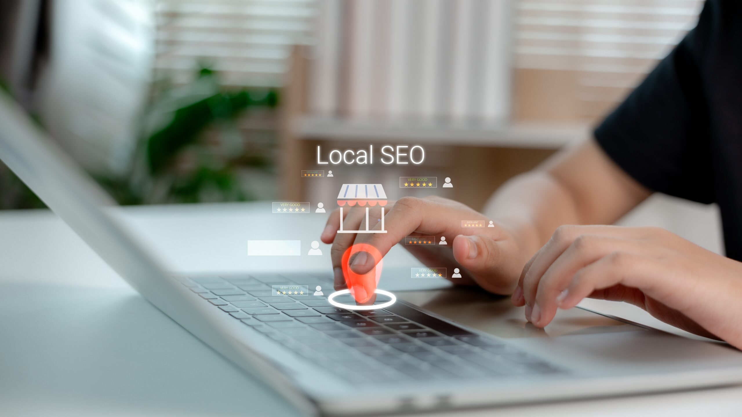 A hand holding an orange chess piece touches a laptop keyboard. Digital graphics show Local SEO with storefront, review, and user avatar icons, symbolizing online local search optimization. Blurred office background.
