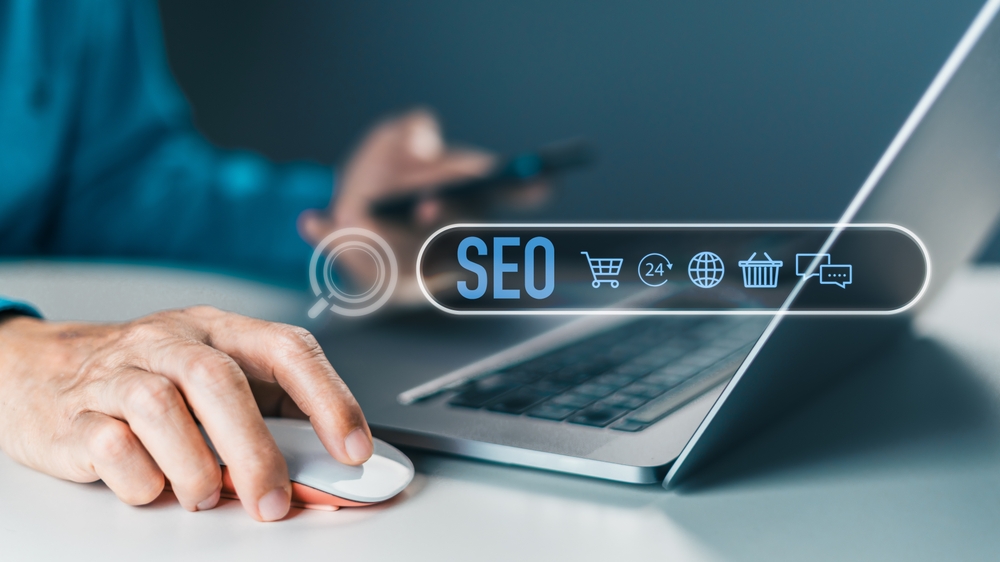 A person uses a laptop and mouse as a transparent search bar overlay shows SEO plus icons for shopping and global search, symbolizing digital marketing and online business.
