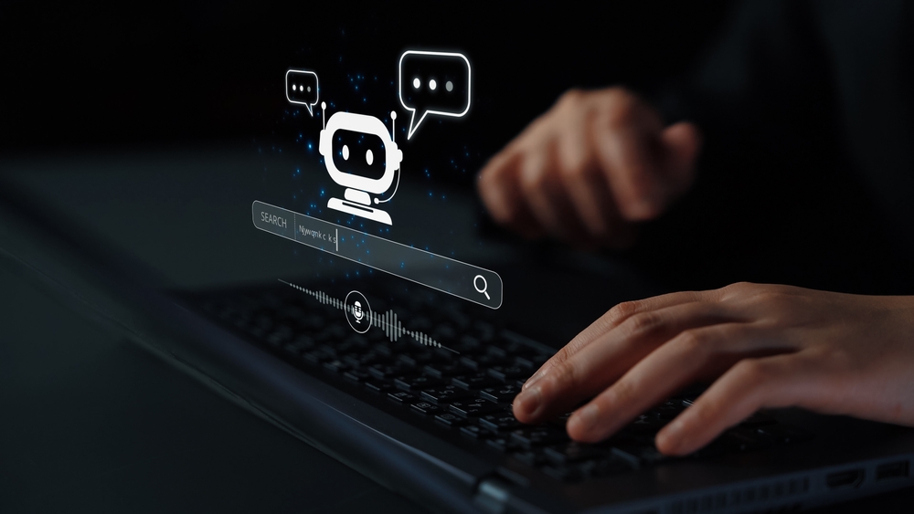 Hands typing on a keyboard with a glowing chatbot icon, speech bubbles, and a search bar digitally overlaid, representing AI communication and search technology on a dark background.