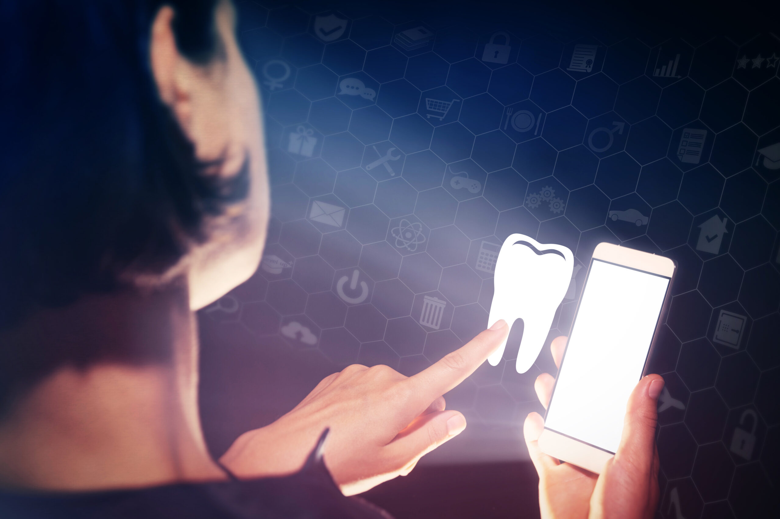 A person holding a smartphone points at a glowing white tooth icon. The background features a dark blue screen overlay with a pattern of hexagonal icons.